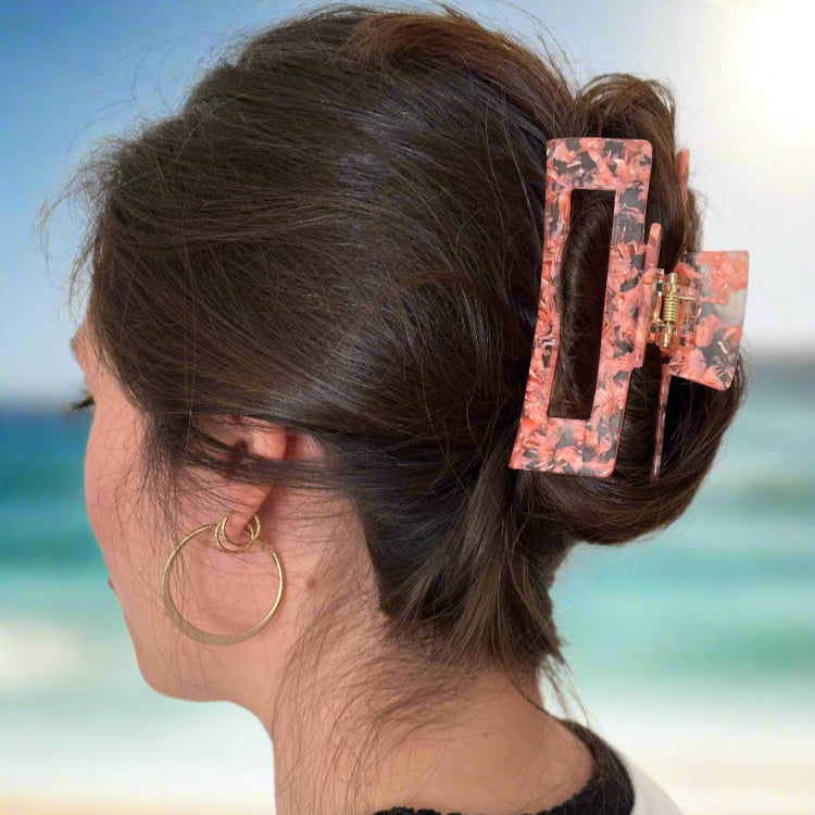 Woman wearing the Peach Gloss hair claw clip, styled in an effortless updo, standing at the beach with natural light.