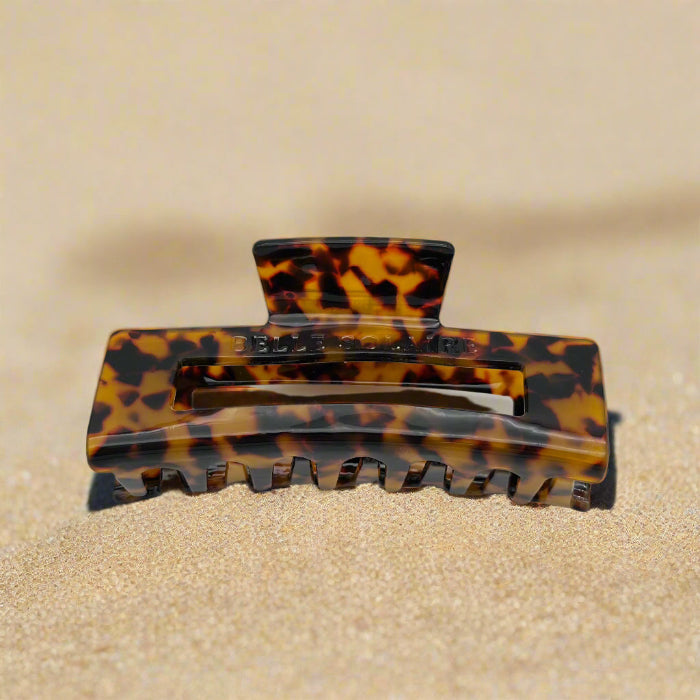Dark tortoiseshell hair claw clip tilted to reveal interlocking claws, made from plant-based cellulose acetate, on beach