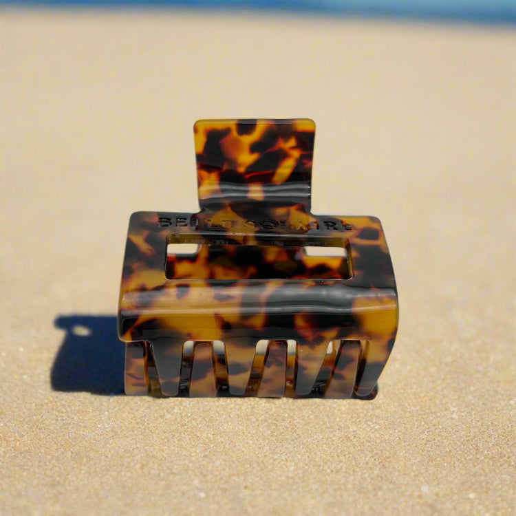 Tortoiseshell hair claw clip tilted to reveal interlocking claws, made from plant-based cellulose acetate, on beach