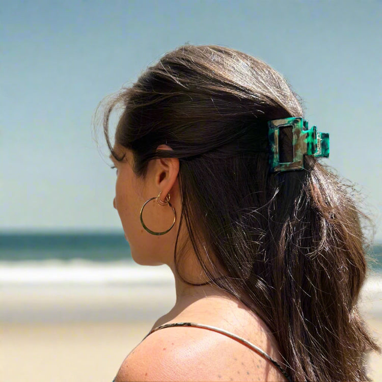 Model wearing the Emerald Grove clip at the beach, styled in long hair for a chic and nature-inspired everyday look.