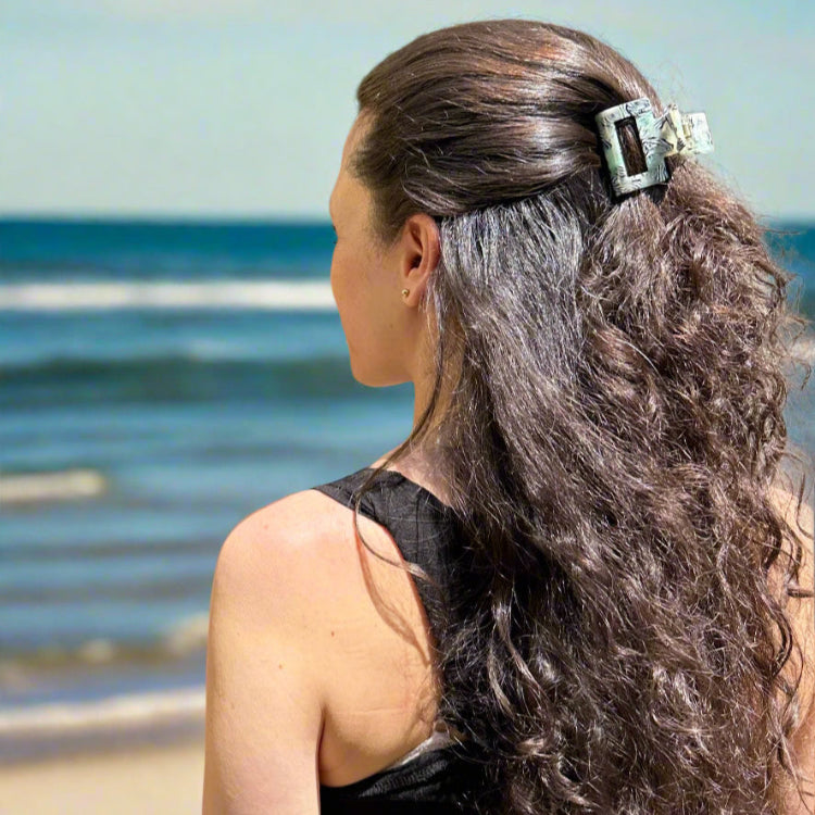 Woman wearing the Zebra Haze hair claw clip, styled in half up, standing at the beach with natural light.