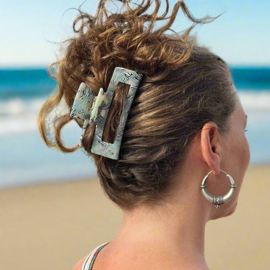 Model wearing a Zebra Haze rectangular hair claw clip, shown from behind at the beach.