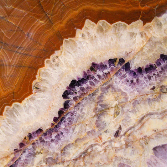 Close-up of natural purple Amethyst crystals surrounded by layers of clear Quartz and warm-toned Agate.