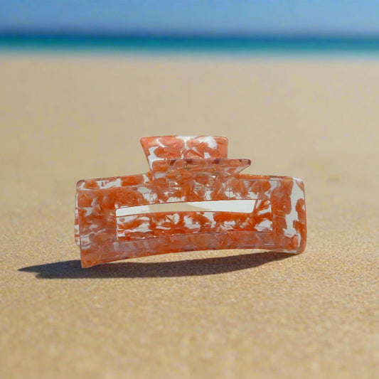 Peach Gloss hair claw clip made from plant-based cellulose acetate, shown in a slightly angled view on beach sand background.