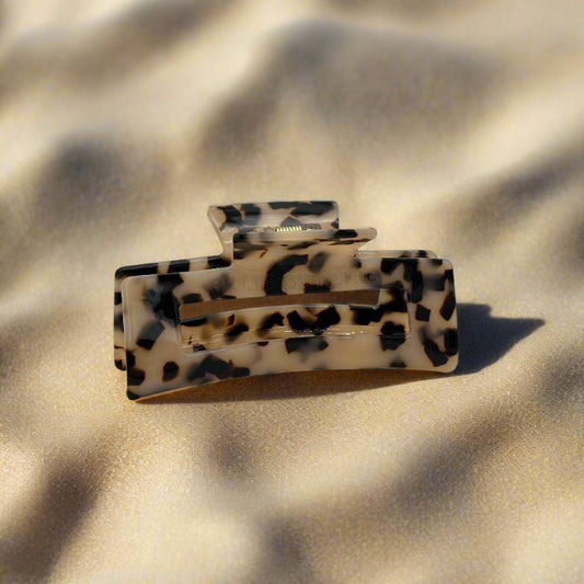 Blonde tortoiseshell rectangular hair claw clip made from plant-based cellulose acetate, displayed on beach