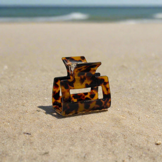 tortoiseshell rectangular hair claw clip made from plant-based cellulose acetate, on beach