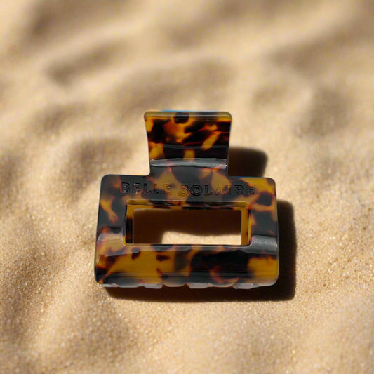 tortoiseshell rectangular hair claw clip made from plant-based cellulose acetate, front view on beach