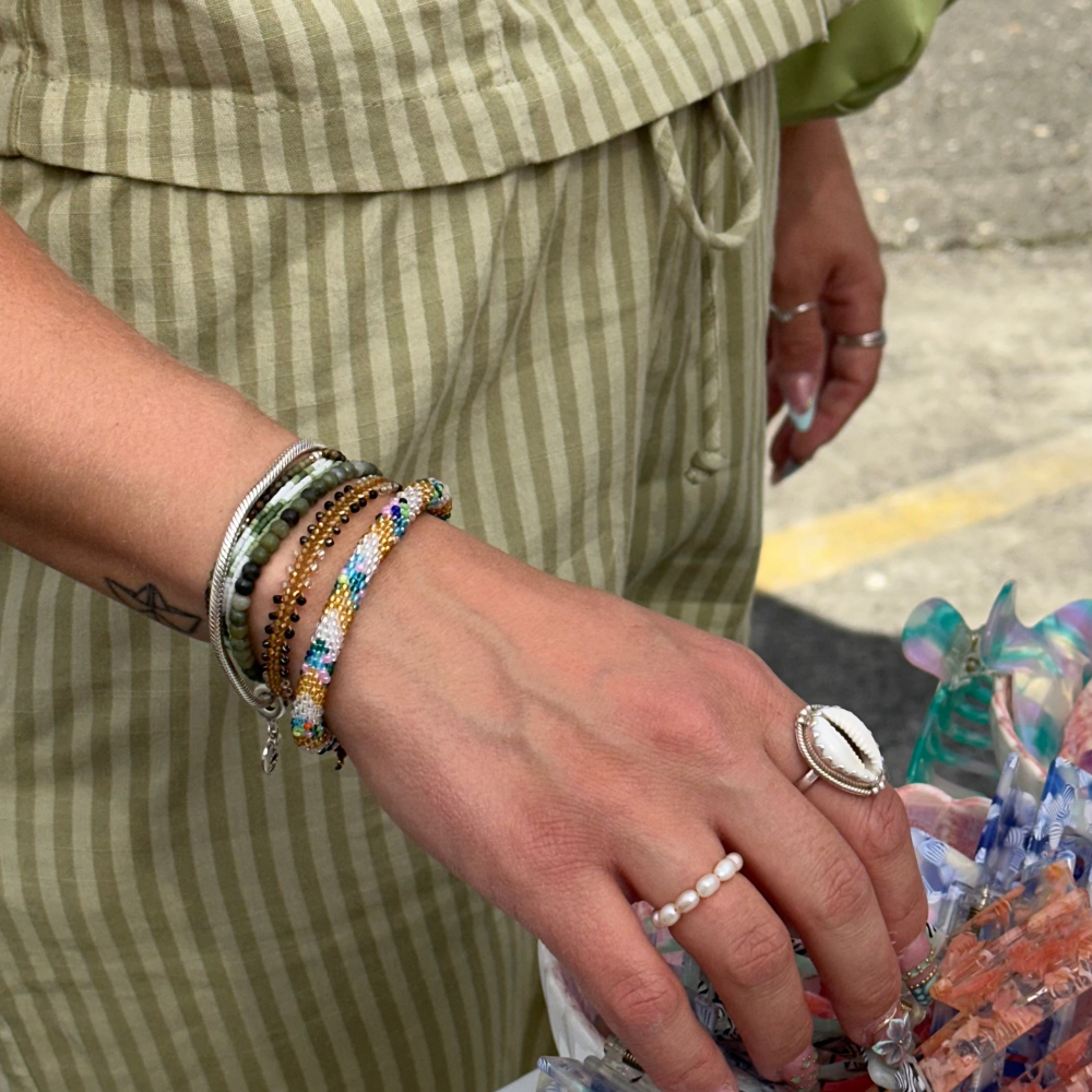 Hand wearing lots of bracelets  and finger rings. Showing the Maya Bracelet from Belle Solaire.