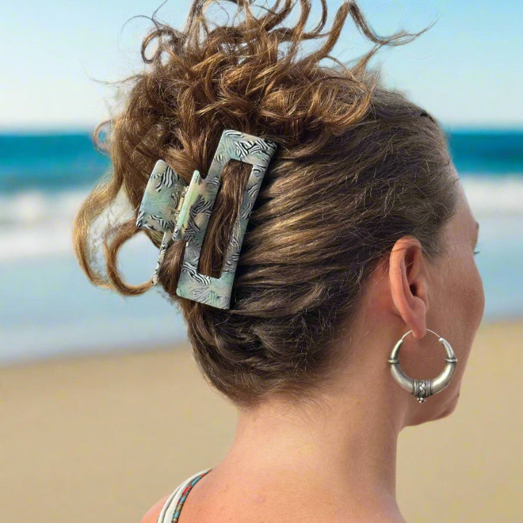 Model wearing a Zebra Haze rectangular hair claw clip, shown from behind at the beach.