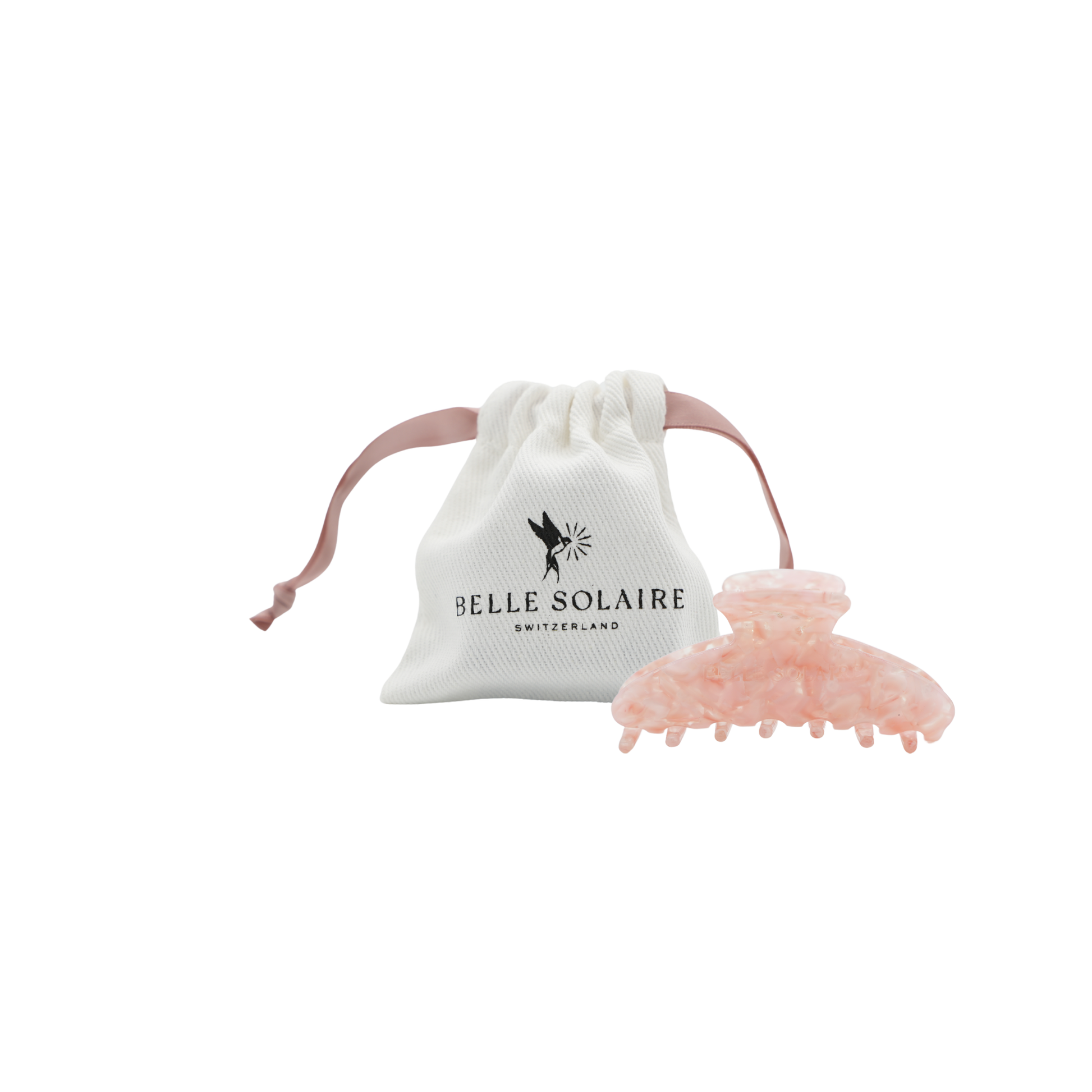 A light pink hair claw clip displayed next to its white drawstring pouch, which features the black printed logo 'BELLE SOLAIRE SWITZERLAND'.