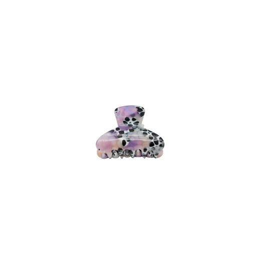 A small hair claw clip with a glossy pattern of black spots on a white base, accented with iridescent lavender and pink shimmer, shown against a plain white background.